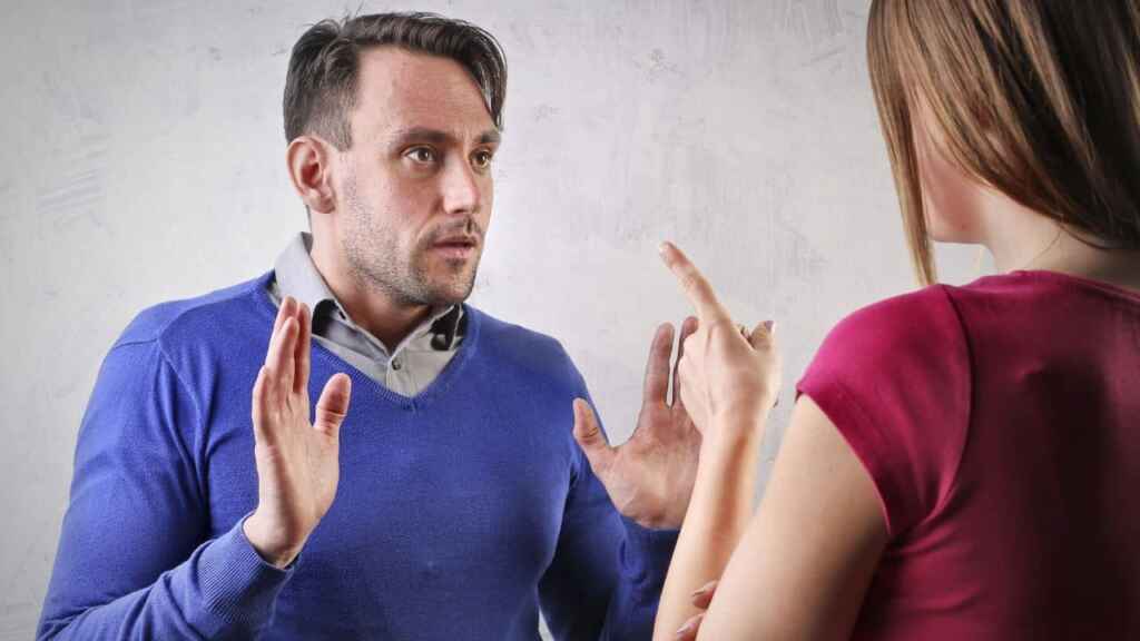 Woman blaming a man pointing a finger in his face. His hands are up