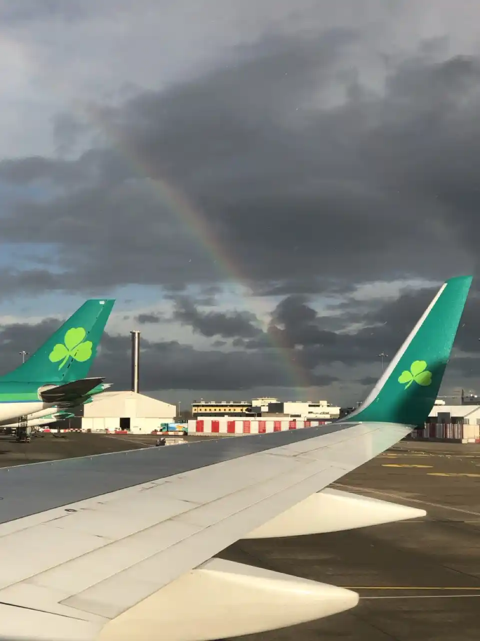 Aer Lingus planes on the tarmac. A rainbow is visible over the wing.