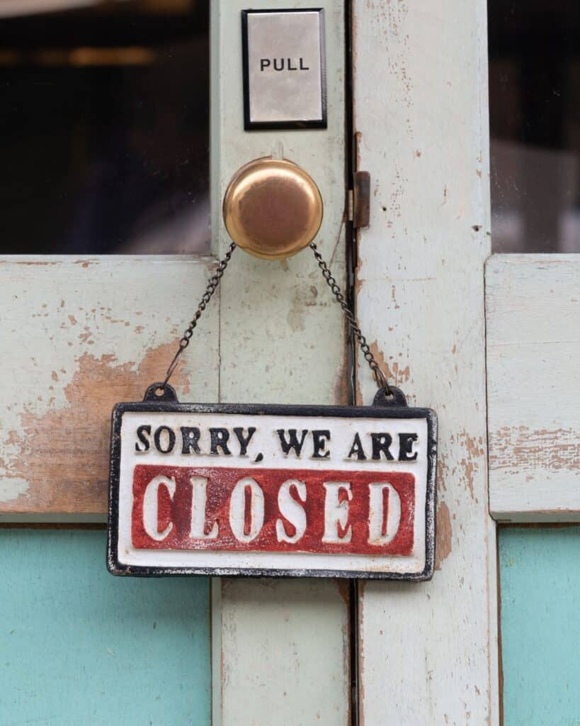 "Sorry we're closed" sign hanging on the doorknob of a business.