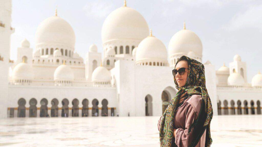 A woman with a headscarf on in front of the Taj Mahal