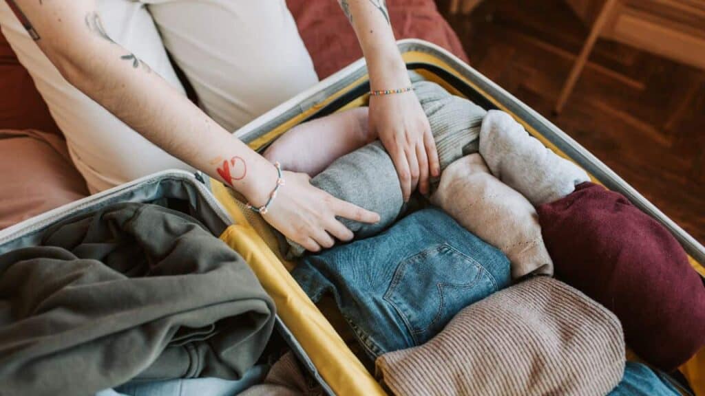 A woman rolling her clothes to pack her suitcase instead of folding.