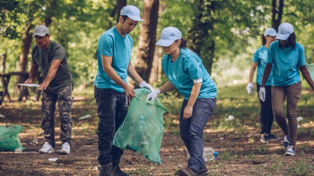 Group of multi-ethnic people, people with differing abilities, volunteers with garbage bags cleaning park area