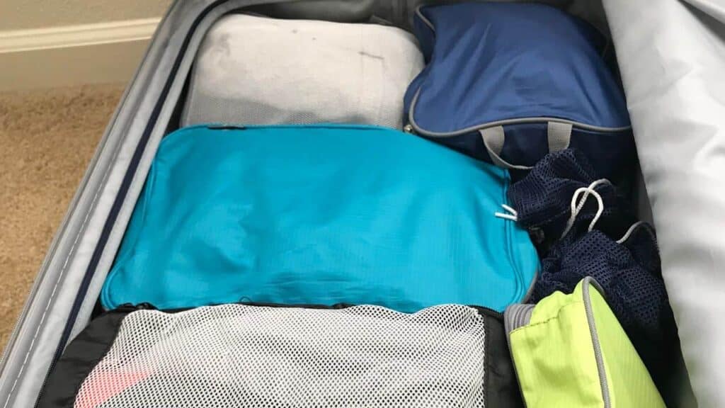 Someone's suitcase packed efficiently with packing cubes in various sizes and colors.