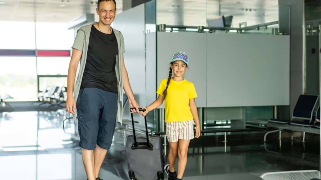 Father and daughter coming through security with their suitcases.