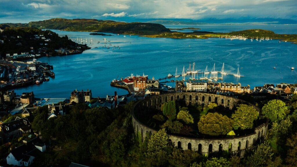 Sunset over sea from Pulpit Hill, Oban. West coast of Scotland. Isle of Kerrera in foreground and ferry sailing from Isle of Mull backlit in background. Argyll and Bute