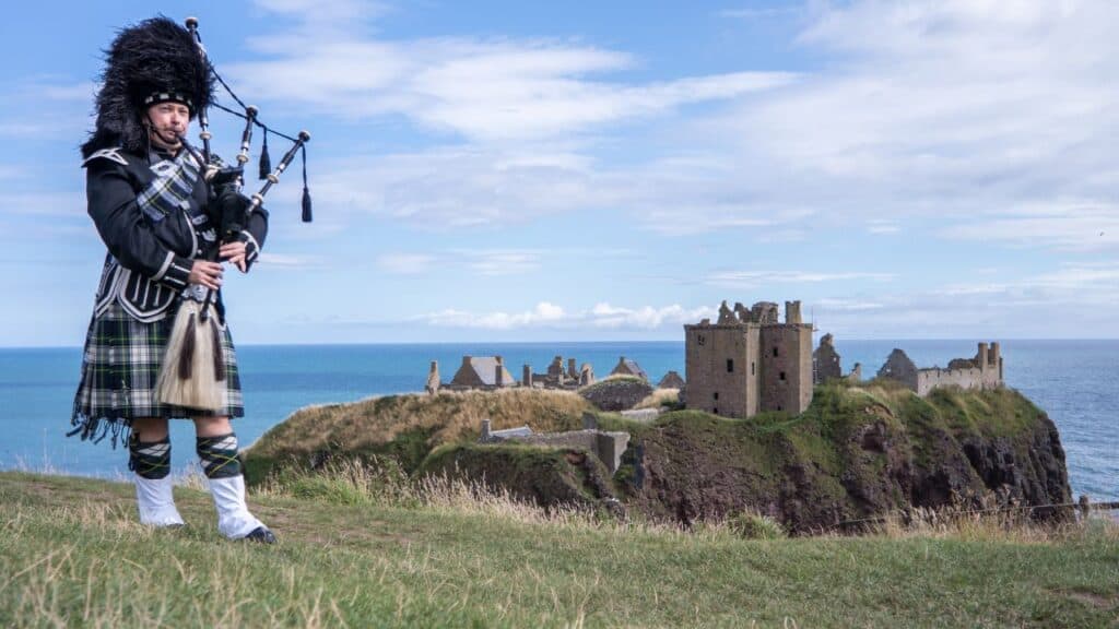 Traditional scottish bagpiper at Dunnottar Castle